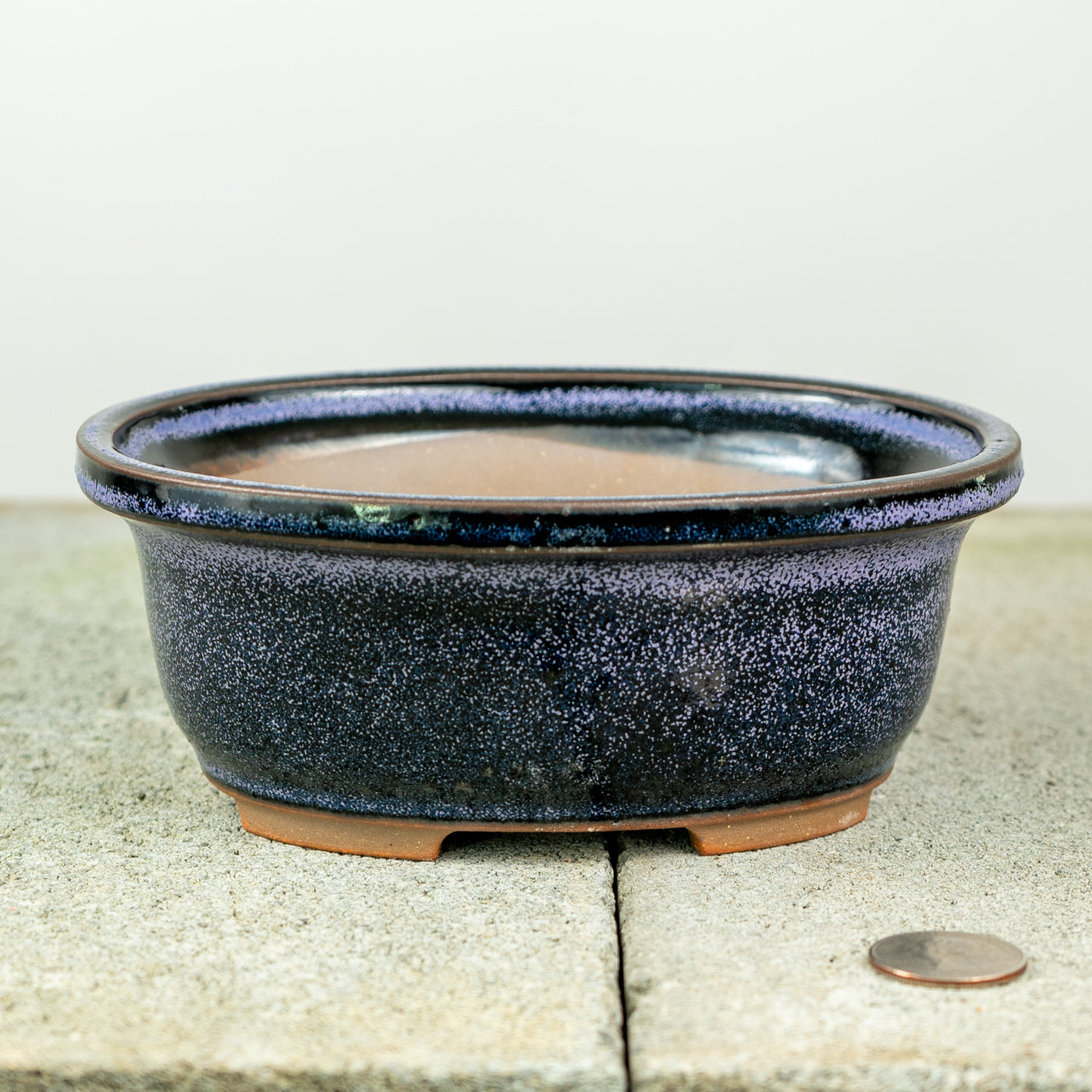 an oval ceramic pot with a dark blue glaze and that shows slight purple